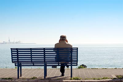 Hombre mayor en un banco que ve pasar la vida en soledad
